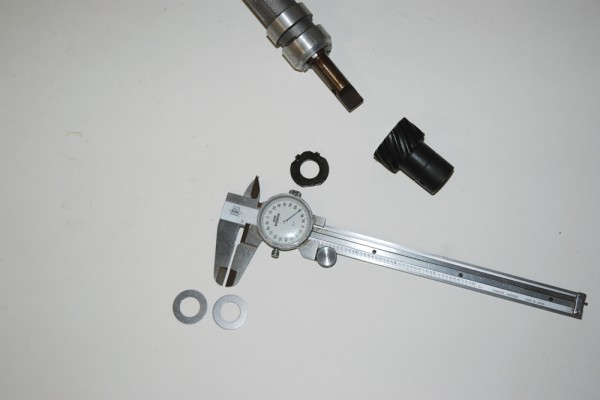 dial caliper next to a distributor shaft and gear