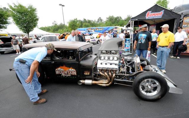 man looking at a supercharged hemi v8 ford hot rod