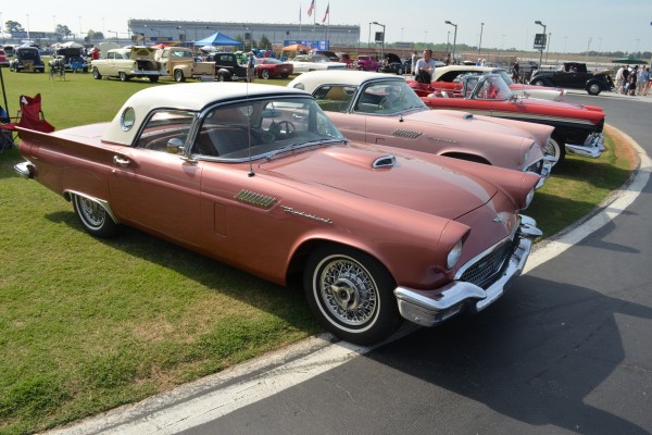 a pair of first gen ford thunderbird coupes at a classic car show