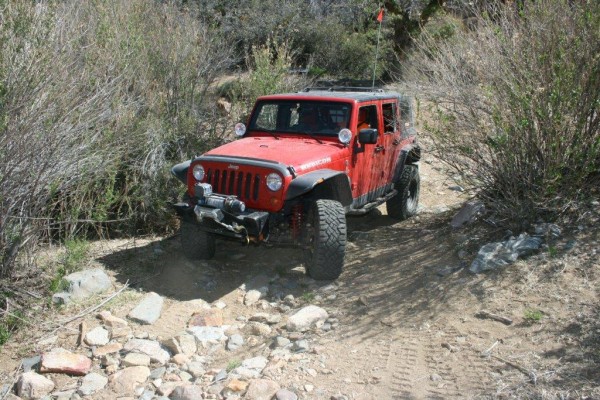 a jeep wrangler jk crossing a rocky desert trail