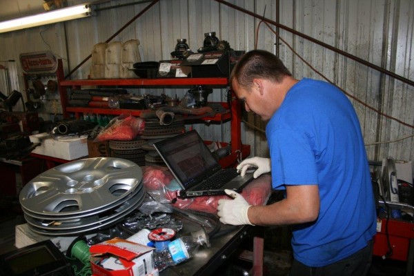 man working on laptop in automotive shop