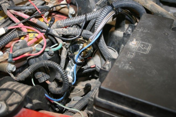 a jumble of wires inside a modern car engine bay