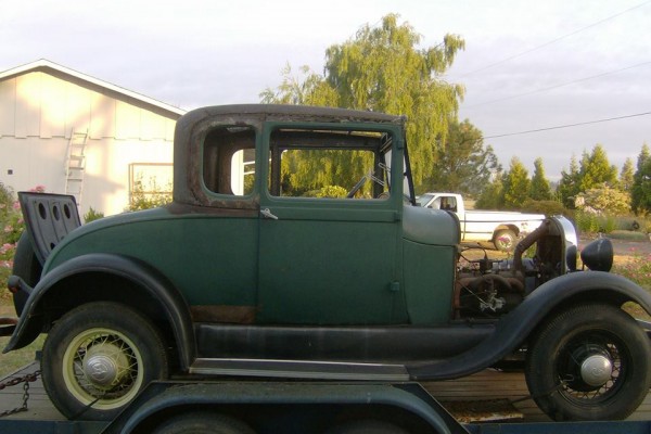 an old ford five window hot rod coupe project car on trailer