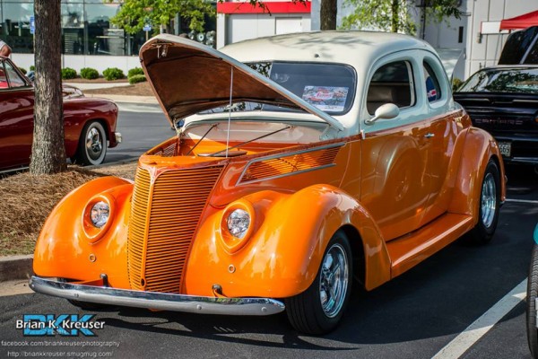 vintage orange and white hot rod coupe at a car show