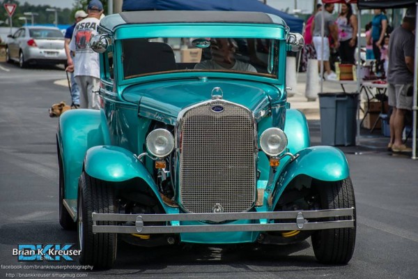 blue ford hotrod coupe being driven into a car show