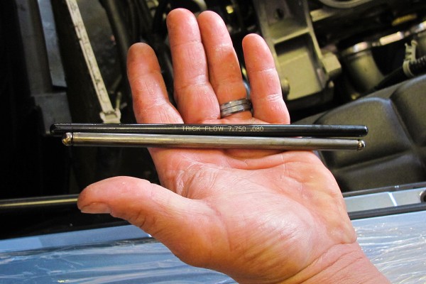 man holding a pair of pushrods for an engine