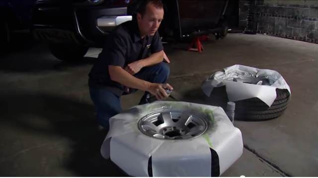 man painting wheels with a rattle spray can