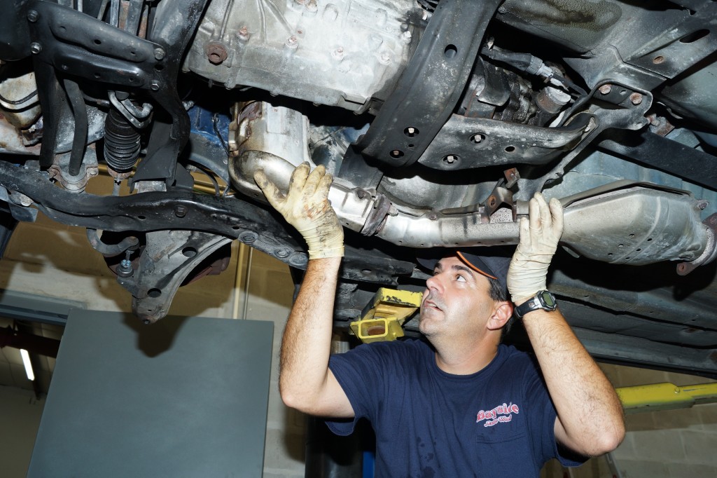 man removing stock exhaust from a subaru wrx on a lift