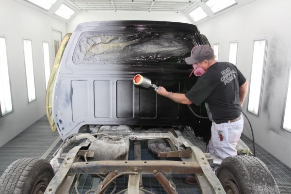 man painting a truck cab in a vehicle spray booth