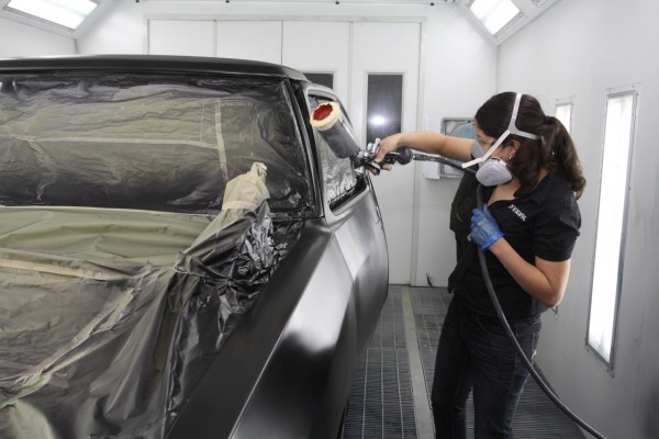 spraying paint onto a truck cab in a spray booth