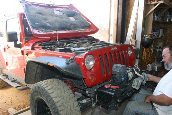 man working on a winch mount for a jeep wrangler jk