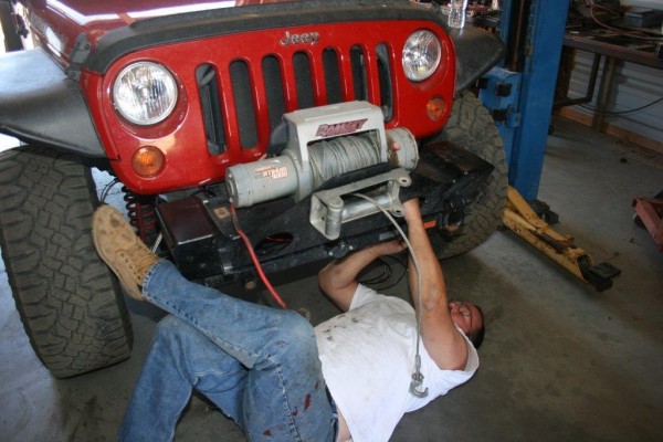 man installing a winch and bumper onto a jeep wrangler jk
