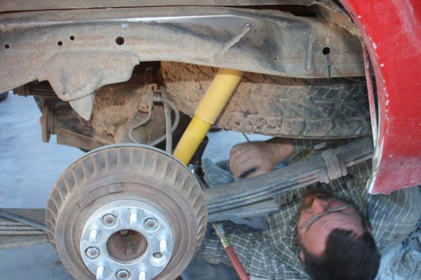 man removing jeep shocks from an old truck