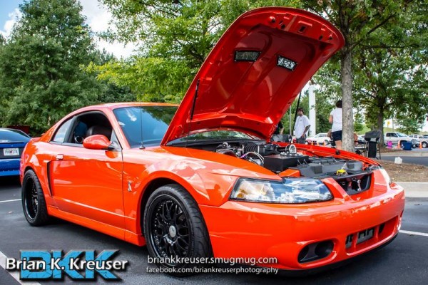 orange new edge sn95 ford mustang at a car show