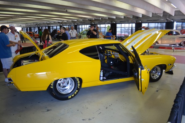yellow Chevy Chevelle drag race car displayed indoors