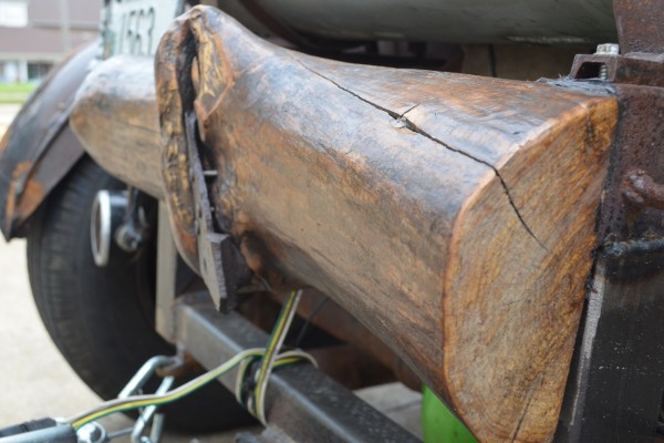 an old wooden log serving as a rear bumper on a rat rod