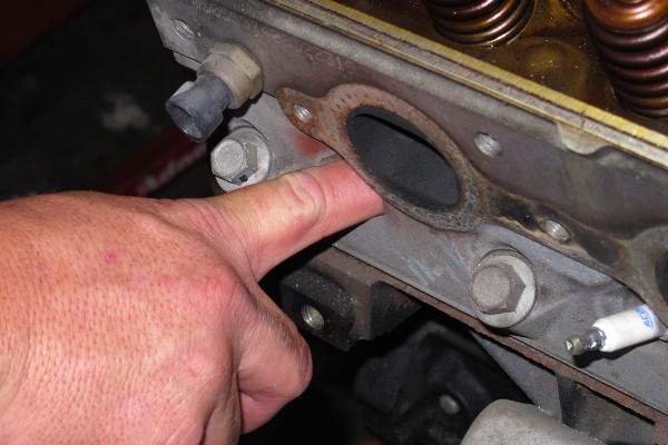 man covering spark plug hole with finger