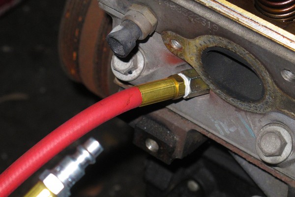 leakdown tester threaded into spark plug port on a cylinder head