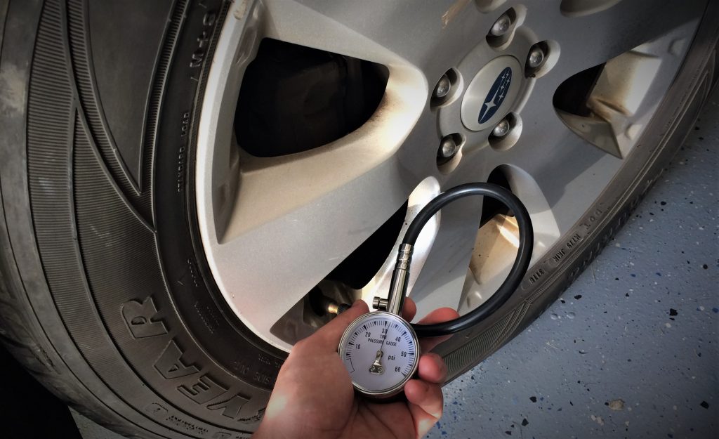 man holding air pressure inflator tire presure gauge to check tire psi