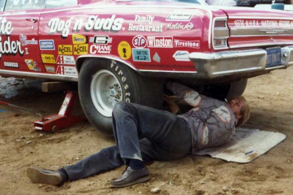 vintage photo of a man working under an old chevy race car