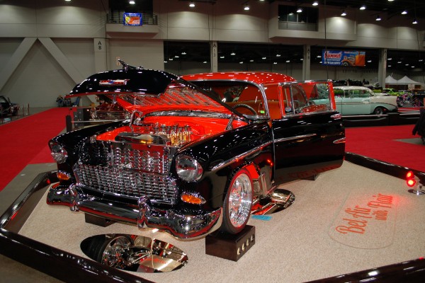 customized black and red 1955 chevy on display in indoor car show