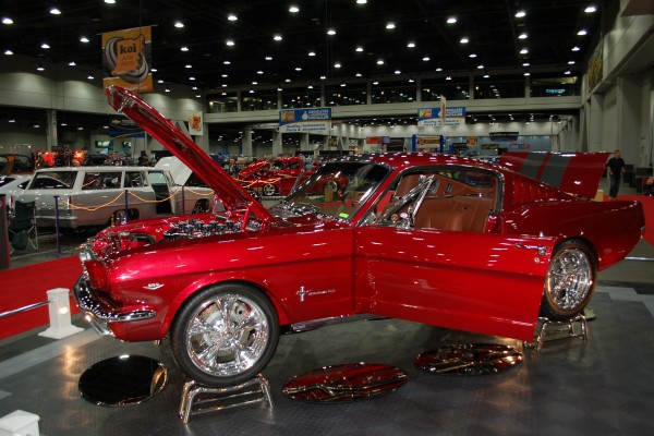 red first gen ford mustang fastback on display in indoor car show