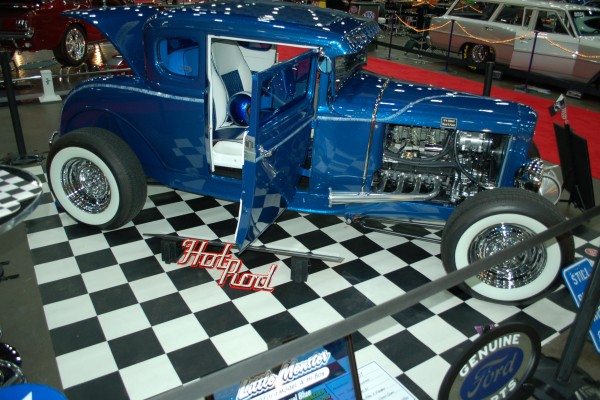 blue ford v8 powered hot rod on display in indoor car show