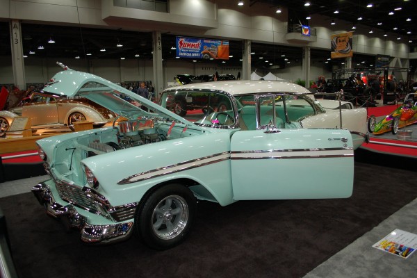 light blue 1956 chevy coupe on display in indoor car show