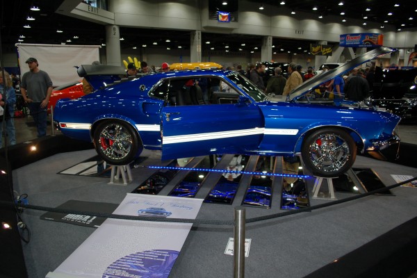 blue 1969 ford mustang on display in indoor car show