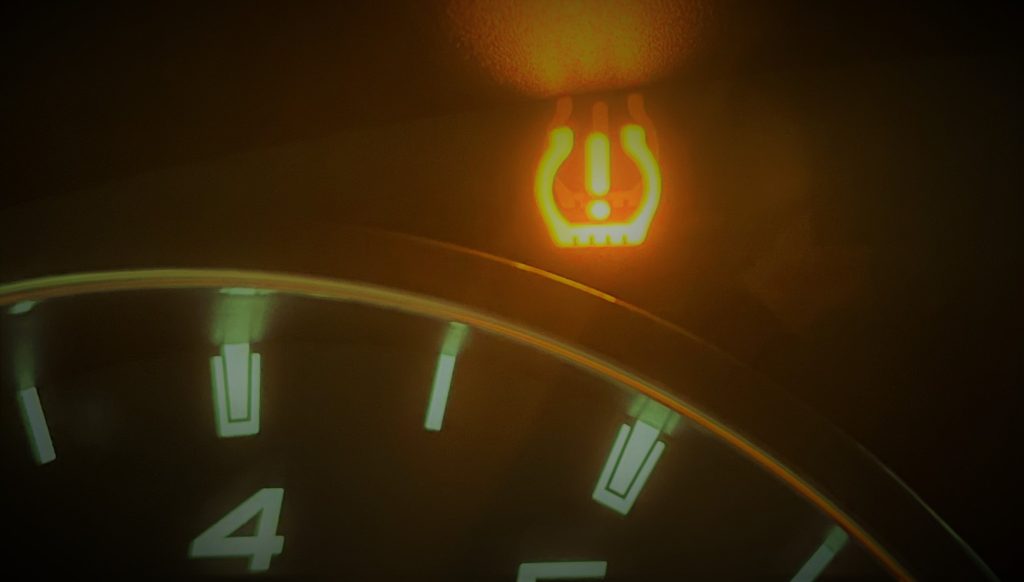stylized photo of a low tire pressure warning light on a car dashboard