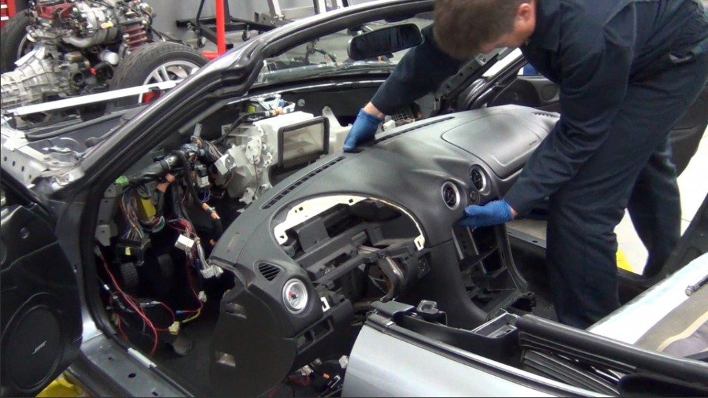 man removing dashboard of a mazda miata