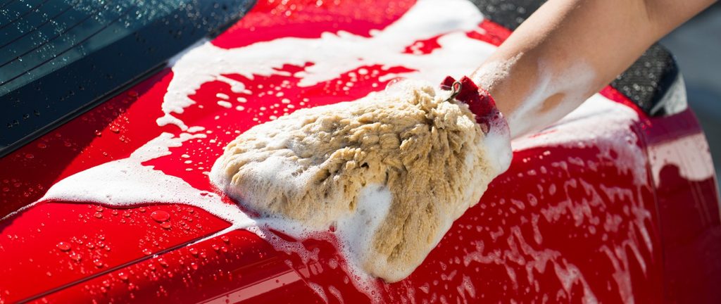 close up of man using car wash mitt with soap