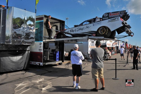 an nhra funny car getting unloaded from a race car semi trailer