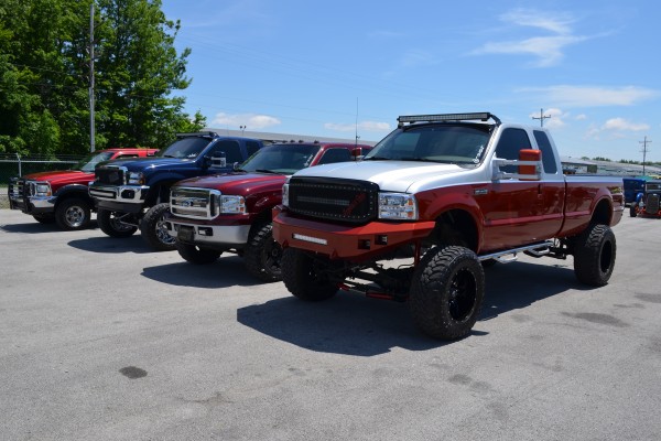 row of lifted trucks at a car show