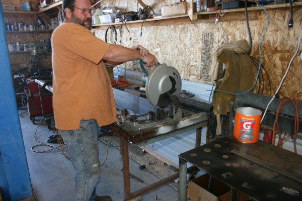 man cutting metal tubing for an aftermarket bumper fabrication