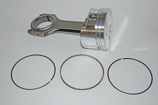 an assembled rod and piston, with rings laid out nearby