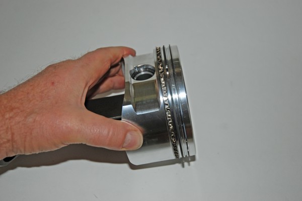 man holding a piston head with rings installed