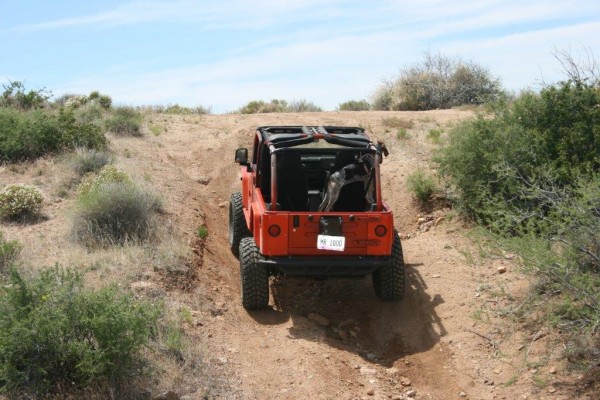 a jeep wrangler climbing up a hill on desert trail
