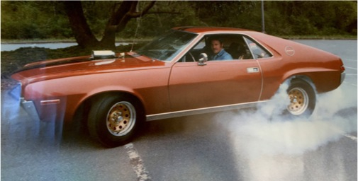 vintage photo of a man doing a burnout in an amc amx muscle car