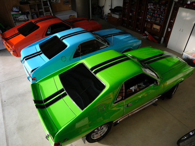 group of three amc amx muscle cars in a garage