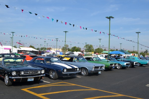 row of vintage muscle cars parked at a cruise in car show