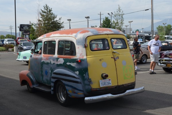 vintage hot rod delivery bus entering parking lot of a car show
