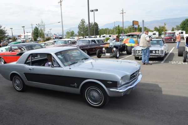 early notchback ford mustang entering parking lot of a car show