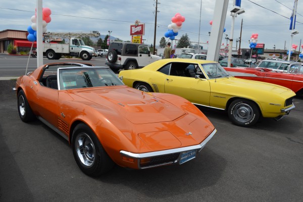 an early c3 corvette stingray and 1969 camaro at a car show