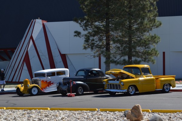 row of classic hot rods parked at a hotel