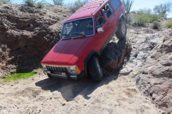 jeep cherokee xj descending a steep desert trail grade