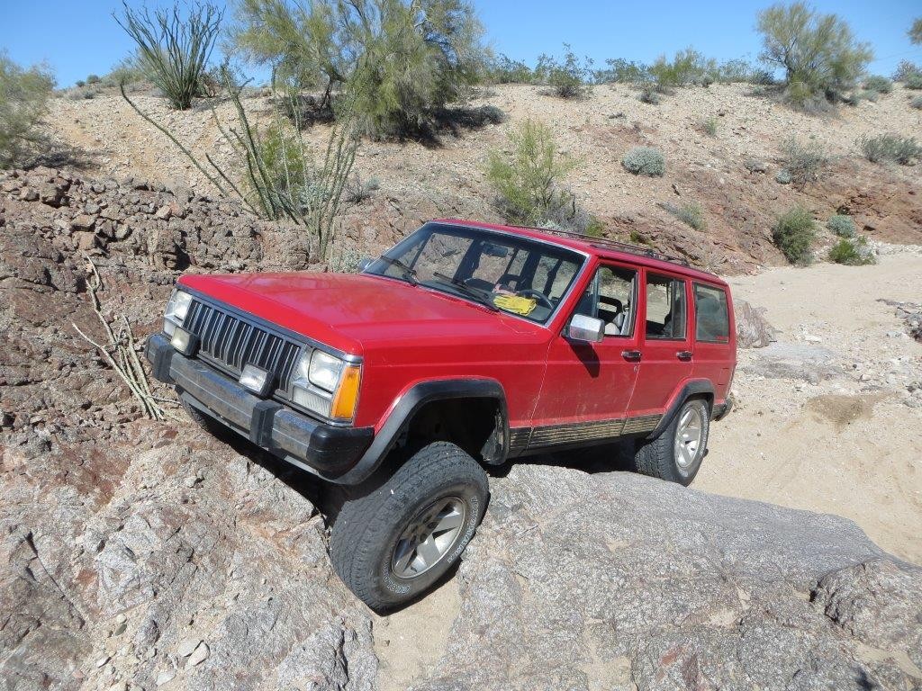 a jeep cherokee xj crawling over rocks and boulders in a desert