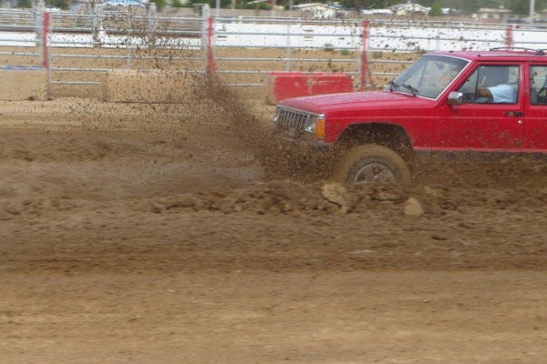 a jeep cherokee xj racing through a mud track