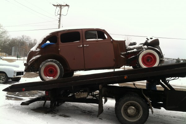 old car on a flatbed trailer covered in snow