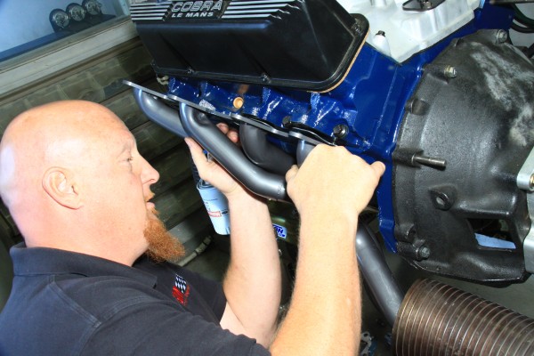 man fitting headers onto a ford fe series 390 engine block